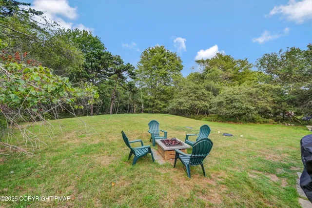 a view of a swimming pool with lawn chairs and a fire pit
