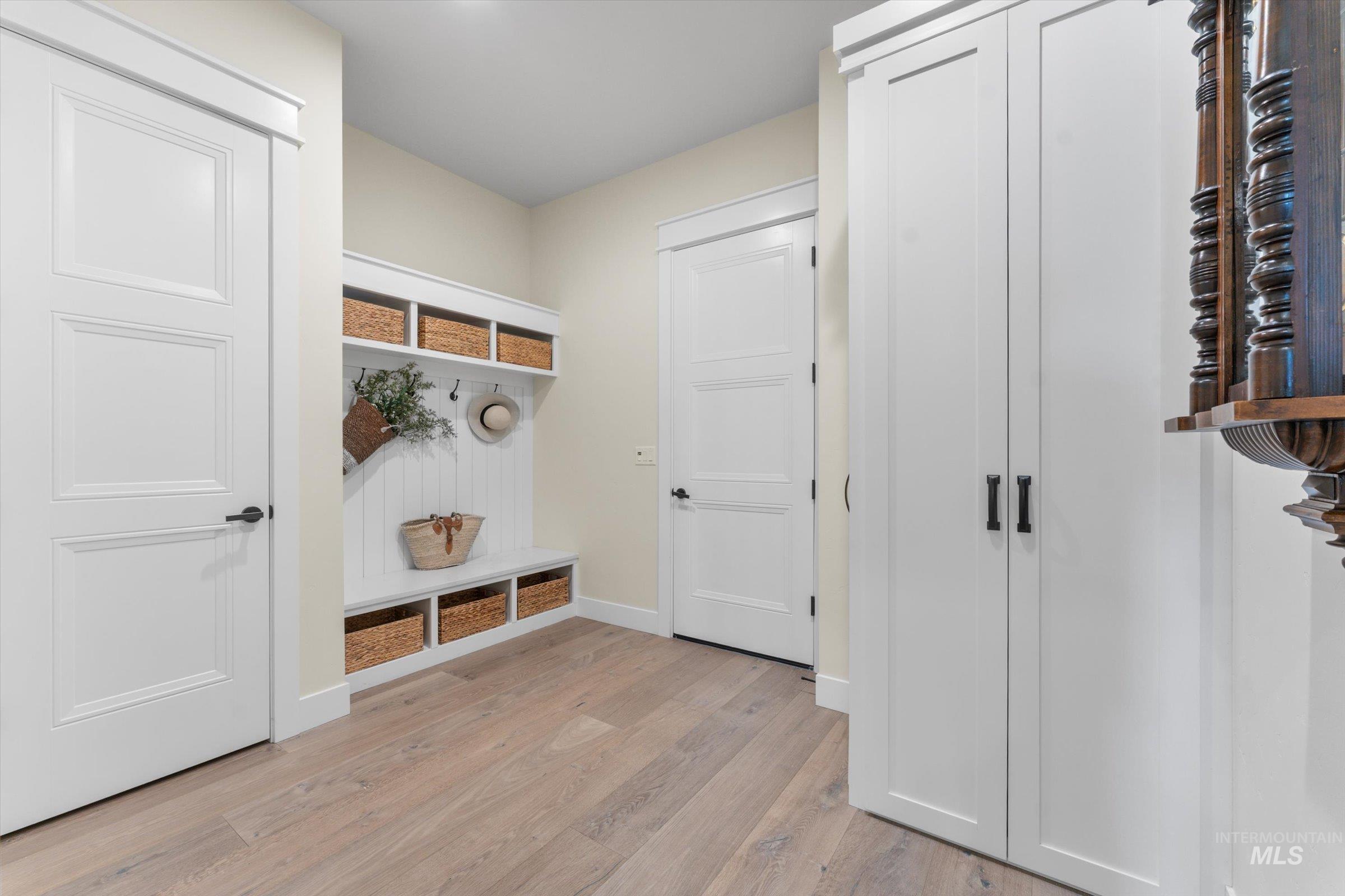 6585 South Pemberley Way Meridian, ID 83642 - Photo 38 of 43 Entryway mudroom featuring built-in white cabinetry, wood-finish flooring, and a bench with integrated storage cubbies