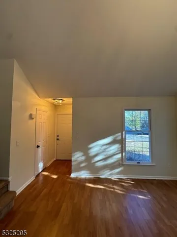 an empty room with wooden floor cabinet and windows