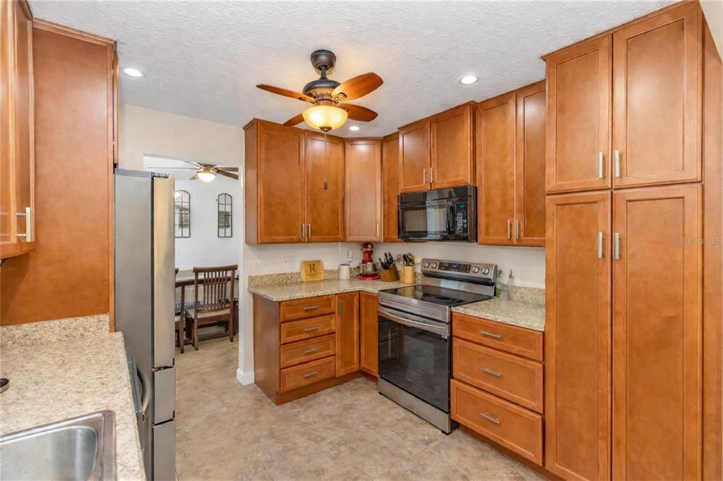 3137 Loblolly Street Deltona, FL 32725 - Photo 8 of 30 a kitchen with stainless steel appliances granite countertop a stove refrigerator and cabinets
