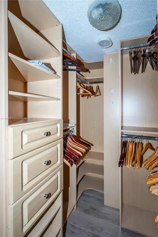 a view of walk in closet with clothes and shoes