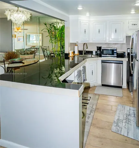 a kitchen with stainless steel appliances granite countertop a refrigerator a sink a stove and white cabinets