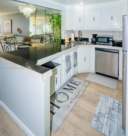 a large white kitchen with stainless steel appliances granite countertop a large counter top a stove and a sink