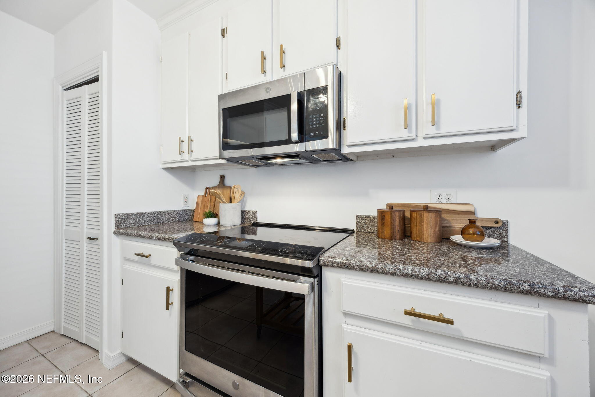 1626 Brookwood Road Jacksonville, FL 32207 - Photo 18 of 98 a kitchen with stainless steel appliances granite countertop white cabinets stove top oven and microwave