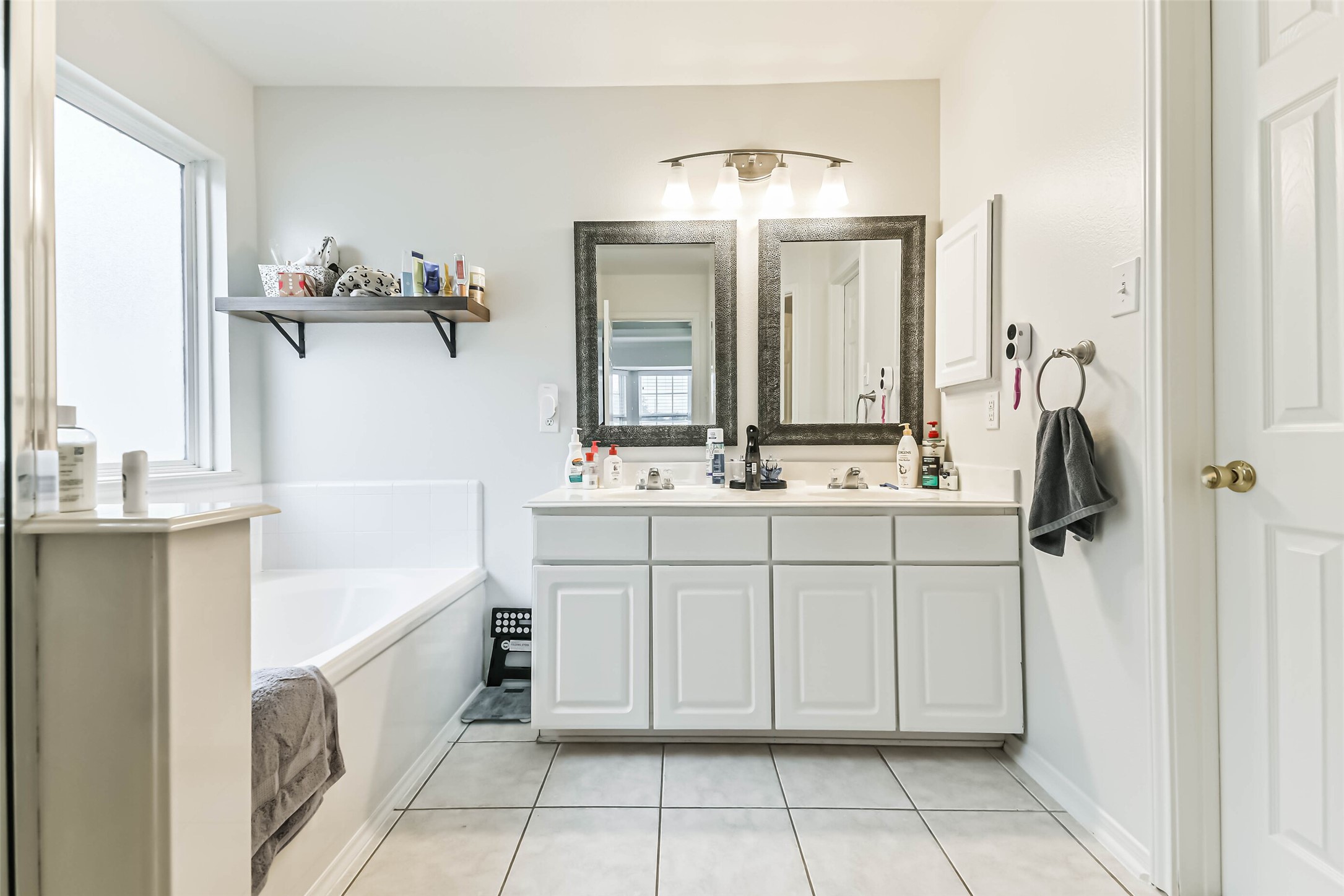 22538 Goss Spring Court Spring, TX 77373 - Photo 27 of 36 Bright and spacious bathroom featuring a double vanity with stylish mirrors, a large soaking tub, and modern fixtures. Ample natural light enhances the clean, contemporary design.