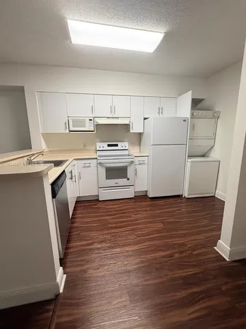 a kitchen with a sink a stove a refrigerator and white cabinets