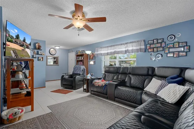a living room with furniture a ceiling fan and a window
