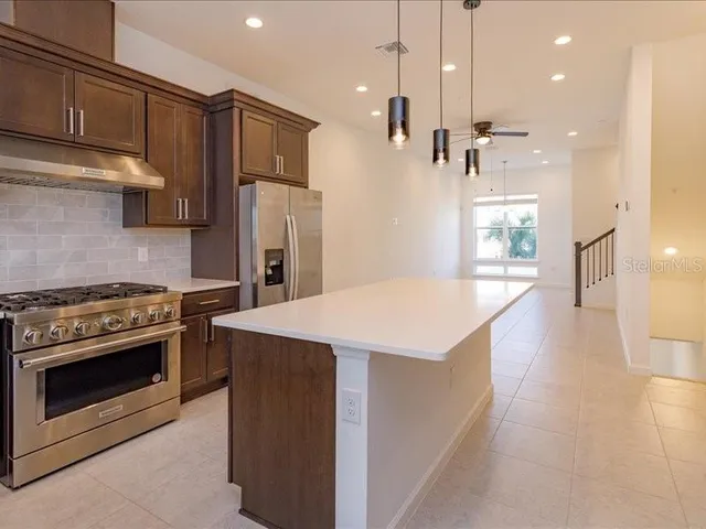 a kitchen with kitchen island a stove a sink a refrigerator and trees