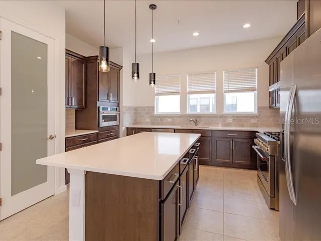 a kitchen with stainless steel appliances granite countertop a refrigerator a sink a stove and a oven