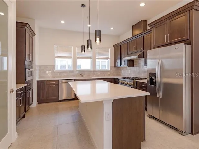 a large kitchen with stainless steel appliances granite countertop a refrigerator a sink a stove and a cabinets
