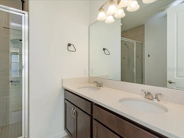 a bathroom with a granite countertop sink a large mirror and a shower