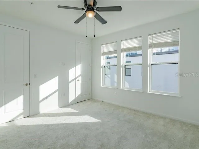 an empty room with windows and fan