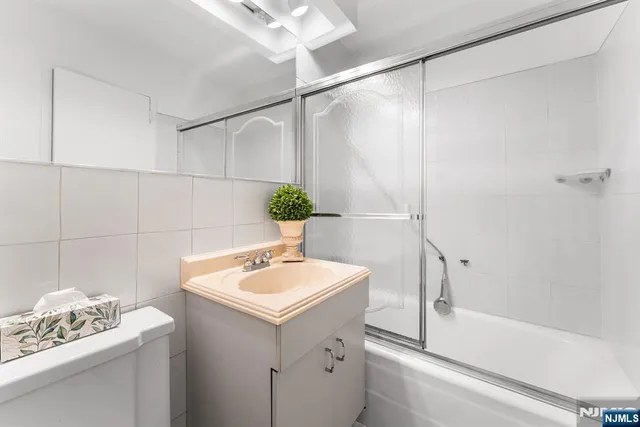 a bathroom with a sink and mirror with bathtub