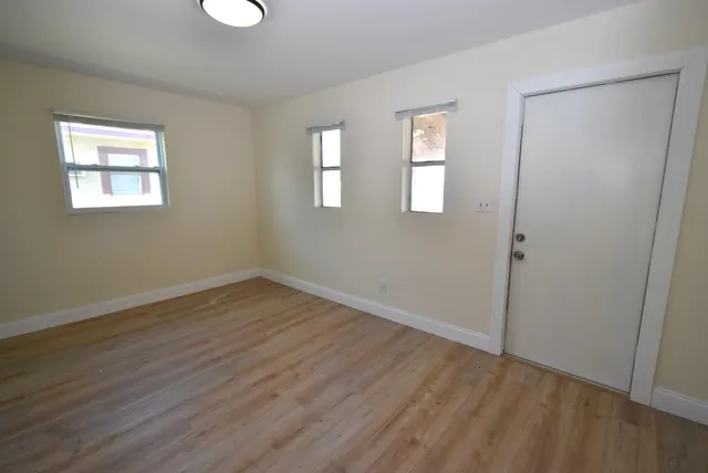 a view of an empty room with wooden floor and a window