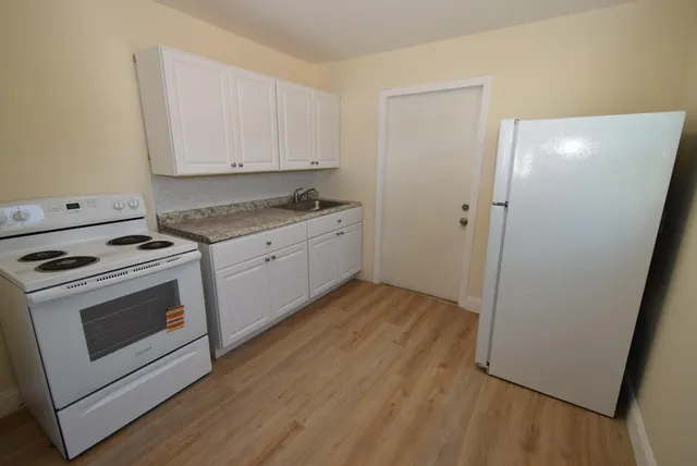 a kitchen with granite countertop white cabinets and white appliances