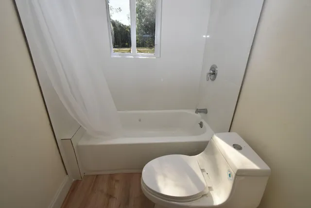 a white toilet sitting next to a bath tub