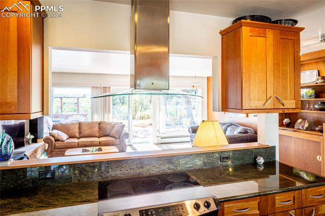 2915 Mt Herman Road Monument, CO 80132 - Photo 11 of 18 Kitchen with dark stone countertops, island range hood, and stainless steel range oven