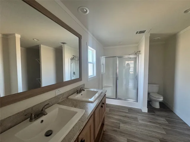 a bathroom with a double vanity sink and mirror with toilet