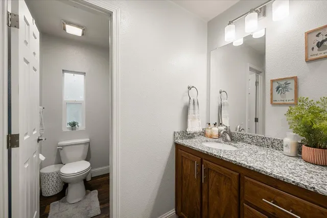 a bathroom with a granite countertop sink a toilet and a mirror