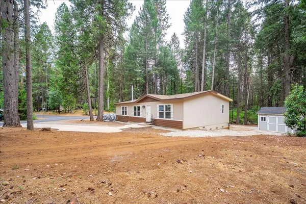a view of a house with a yard and large trees