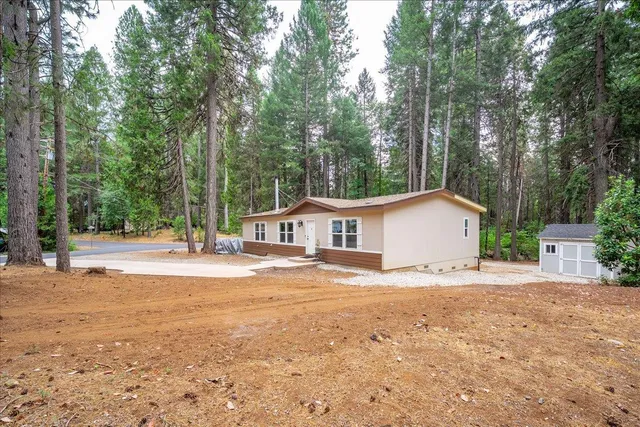a view of a house with a yard and large trees