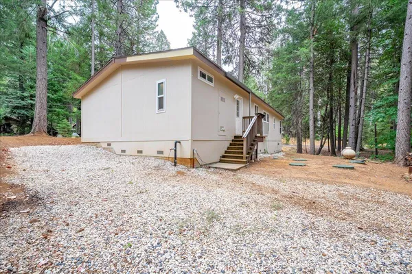 a view of backyard of house with wooden fence and trees
