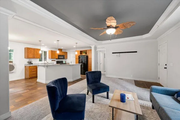a living room with furniture kitchen view and a chandelier
