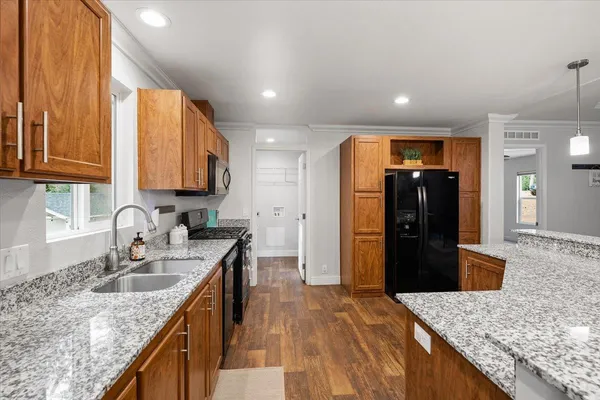 a kitchen with kitchen island granite countertop a sink stove and refrigerator