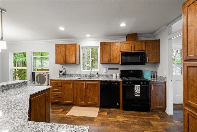 a kitchen with stainless steel appliances granite countertop a stove top oven a sink dishwasher a dining table and chairs with wooden floor