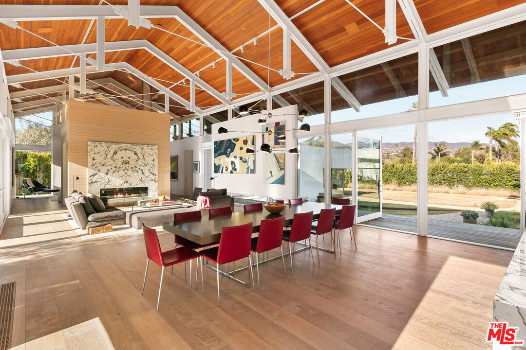 6728 Wildlife Road Malibu, CA 90265 - Photo 6 of 57 a dining room with wooden floor a chandelier a glass table and chairs