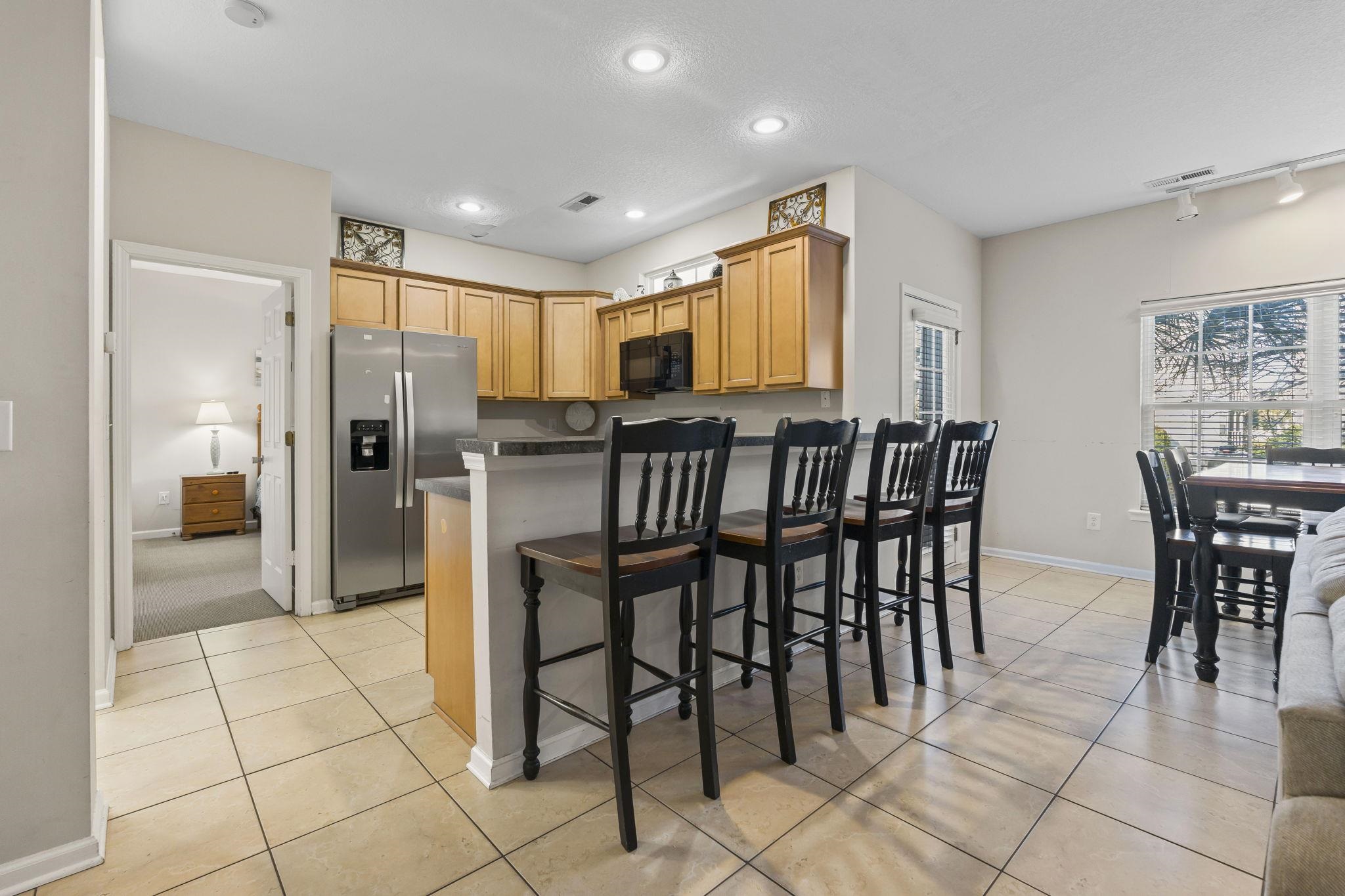 311 B 3rd Avenue North Surfside Beach, SC 29575 - Photo 15 of 39 Kitchen with a kitchen bar, stainless steel refrigerator with ice dispenser, light tile patterned flooring, dark countertops, and black microwave
