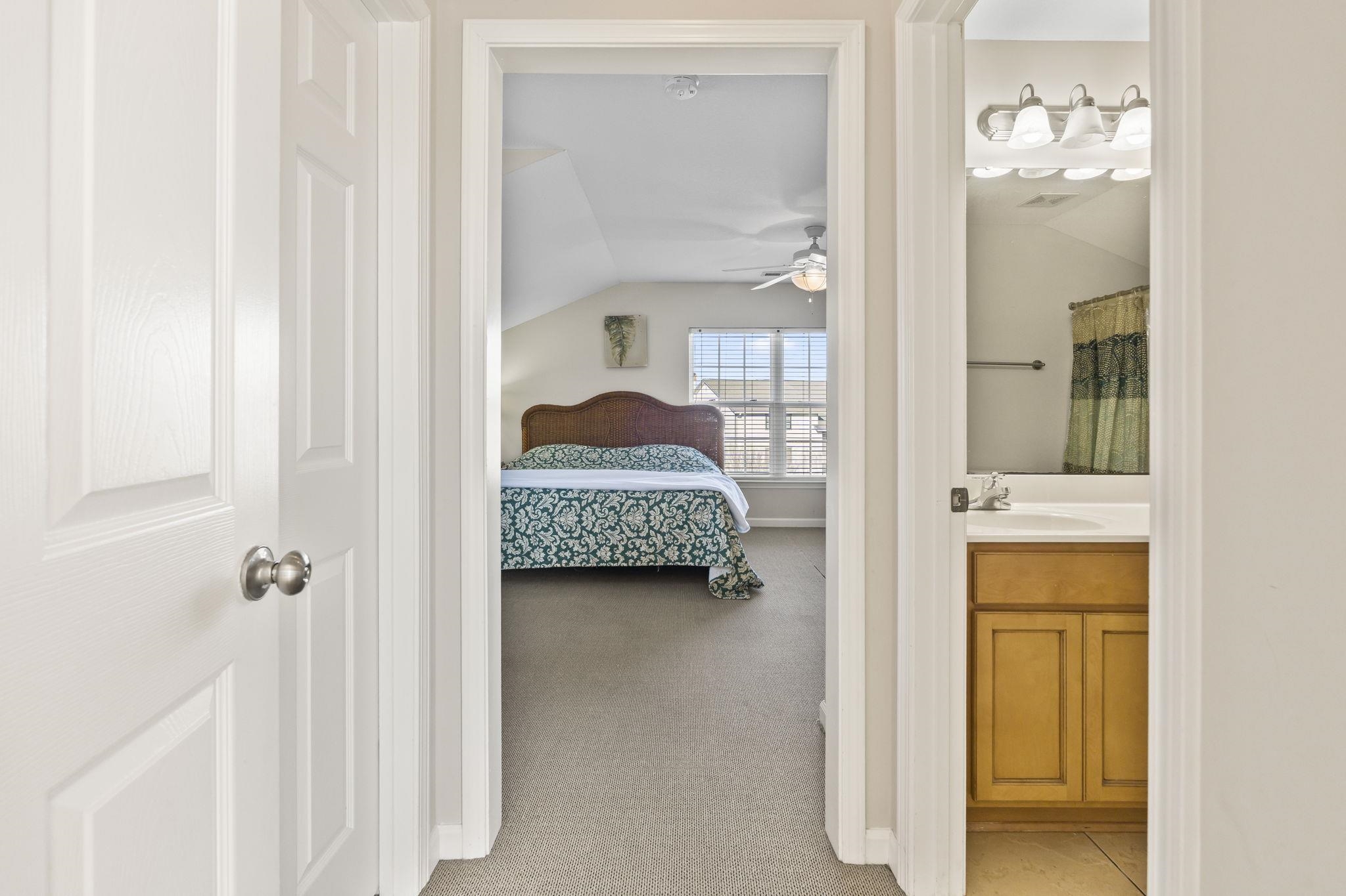 311 B 3rd Avenue North Surfside Beach, SC 29575 - Photo 29 of 39 Bedroom featuring vaulted ceiling, light carpet, and ensuite bath