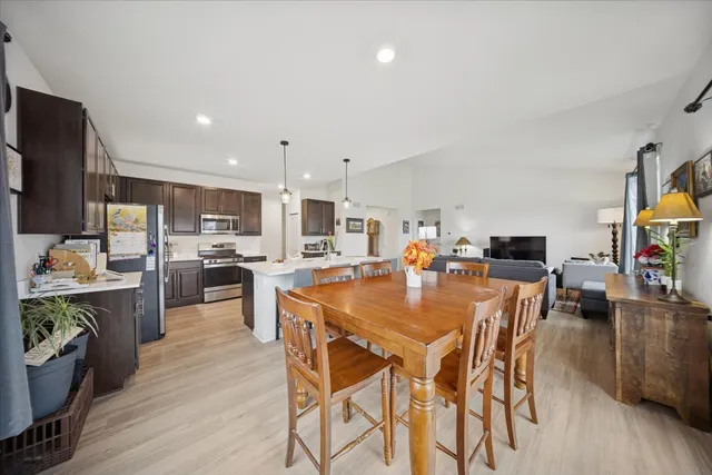 a view of a dining room and livingroom with furniture wooden floor a rug a painting and a chandelier