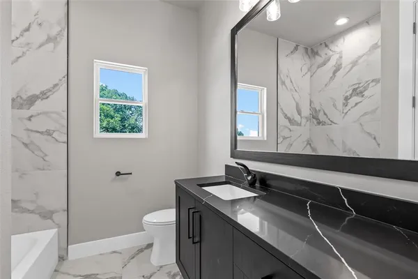 a bathroom with a granite countertop sink toilet and shower