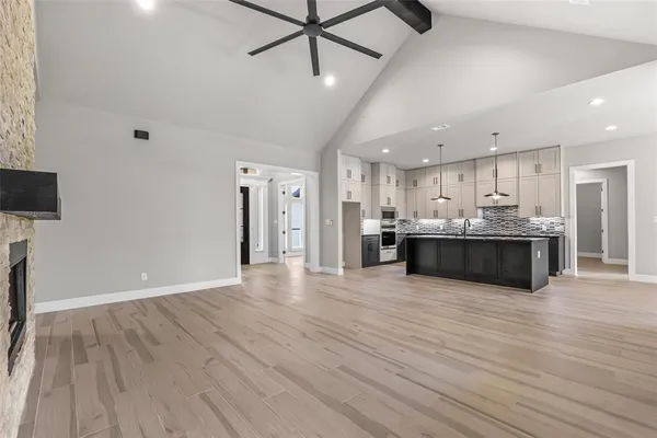 a large kitchen with stainless steel appliances granite countertop a large counter top a wooden floors and a fireplace