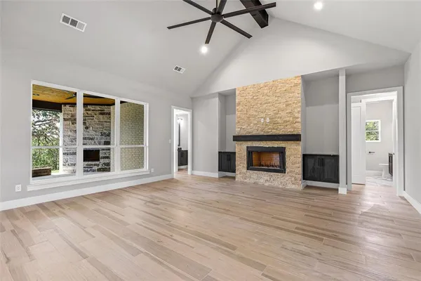a view of an empty room with wooden floor fireplace and a window