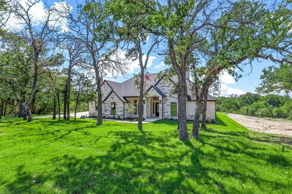 a front view of a house with a yard and trees