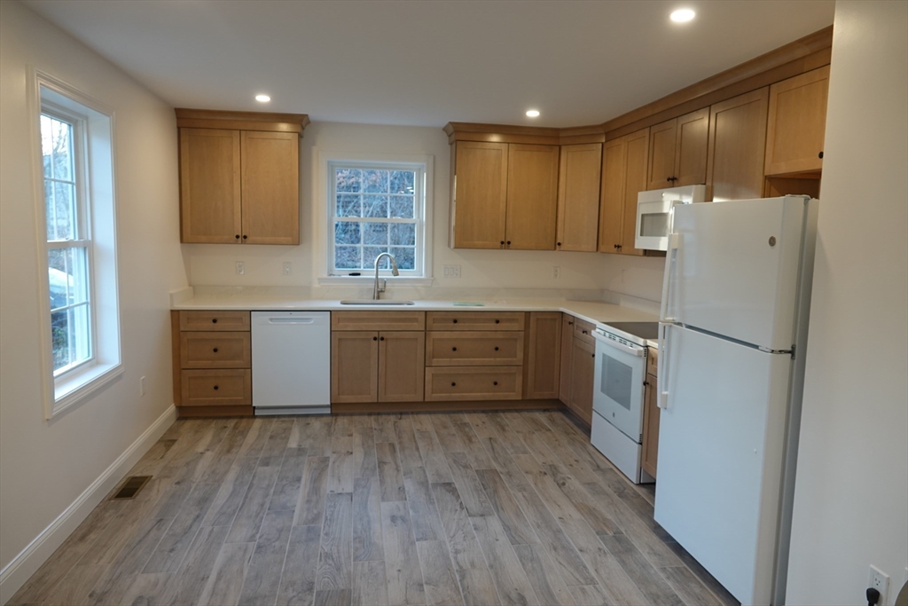 6 Pondover Road, Unit ADU Billerica, MA 01821 - Photo 2 of 20 a kitchen with a refrigerator a sink and wooden cabinets