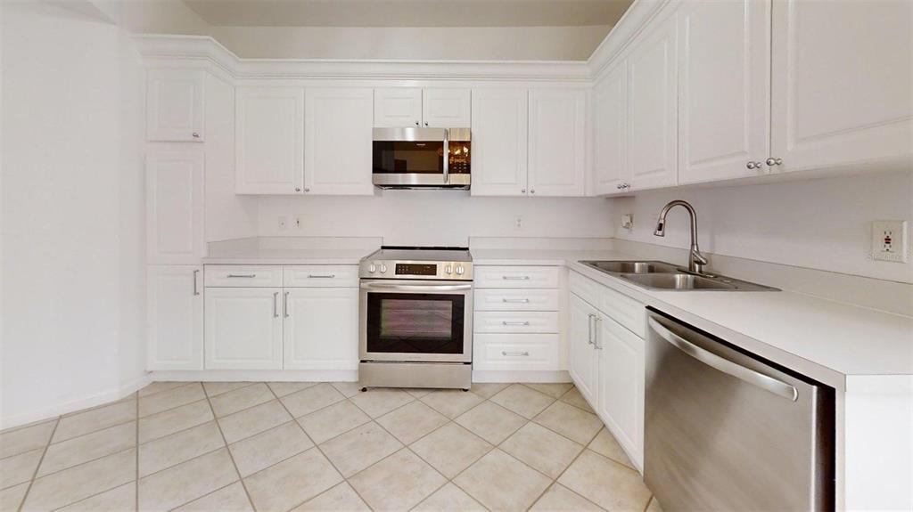 460 Water Street, Unit 460 Celebration, FL 34747 - Photo 7 of 38 a kitchen with white cabinets stainless steel appliances and sink