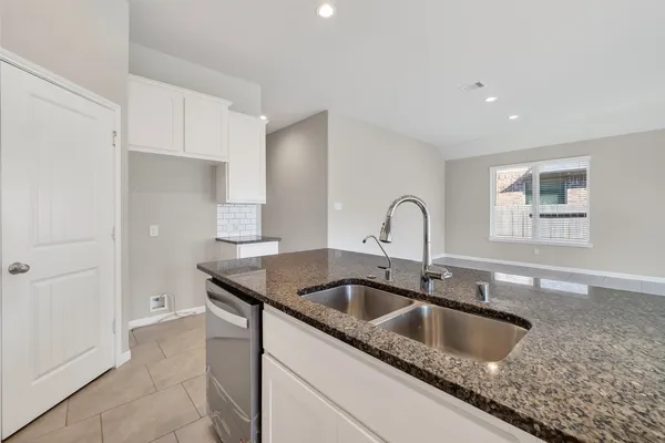 a kitchen with granite countertop a sink and a refrigerator