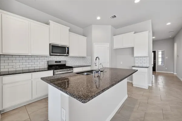a kitchen with kitchen island granite countertop a sink a counter top space appliances and cabinets