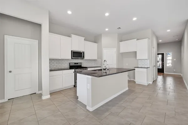 a large kitchen with stainless steel appliances granite countertop a stove a sink and a refrigerator