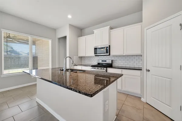 a kitchen with kitchen island granite countertop a sink a stove and cabinets