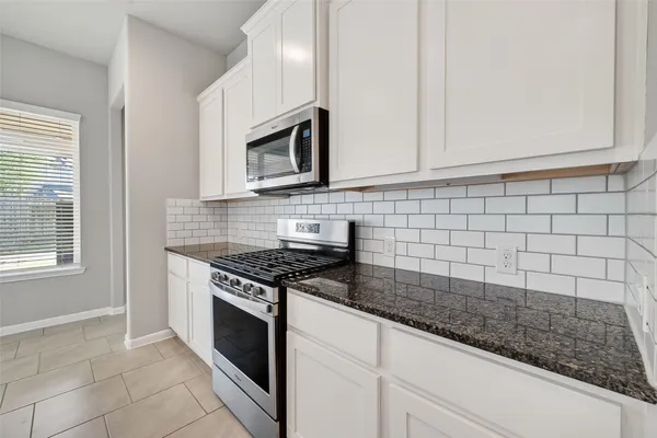 a kitchen with granite countertop white cabinets stainless steel appliances and a sink