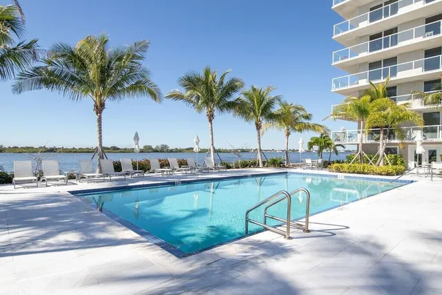 a view of a swimming pool with a chair and palm trees