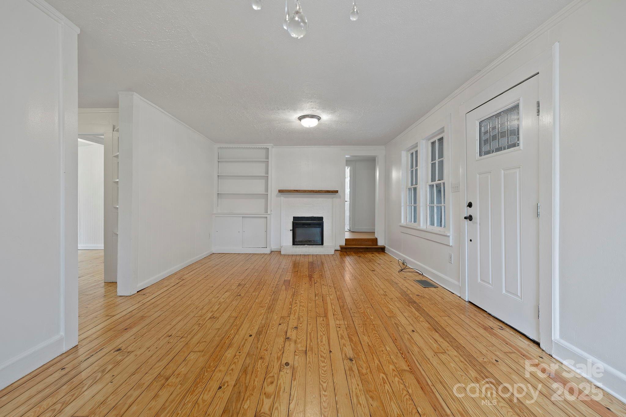 21 Maple Street Brevard, NC 28712 - Photo 13 of 29 a view of empty room with wooden floor and fireplace