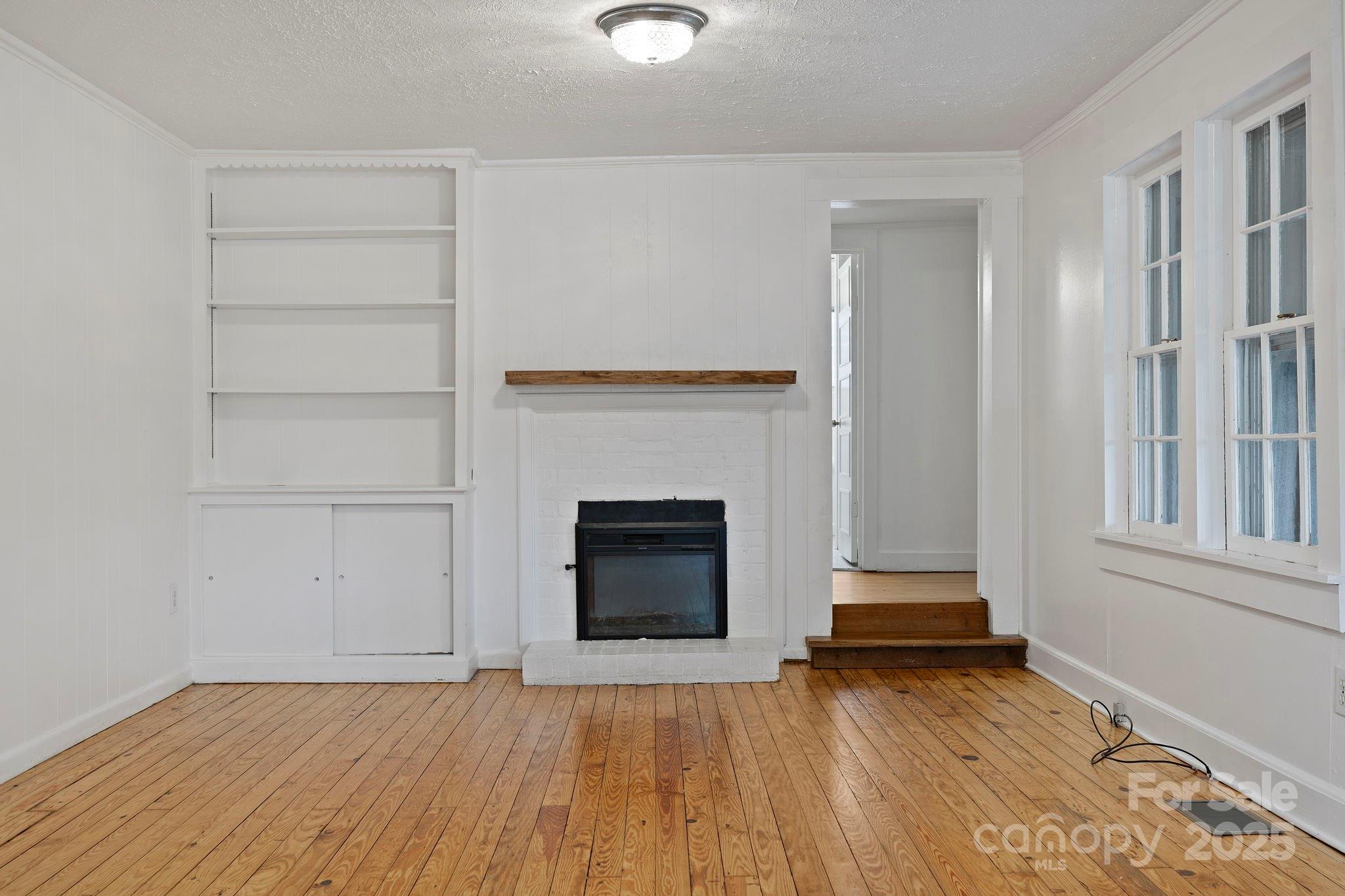 21 Maple Street Brevard, NC 28712 - Photo 15 of 29 an empty room with wooden floor a fireplace and windows