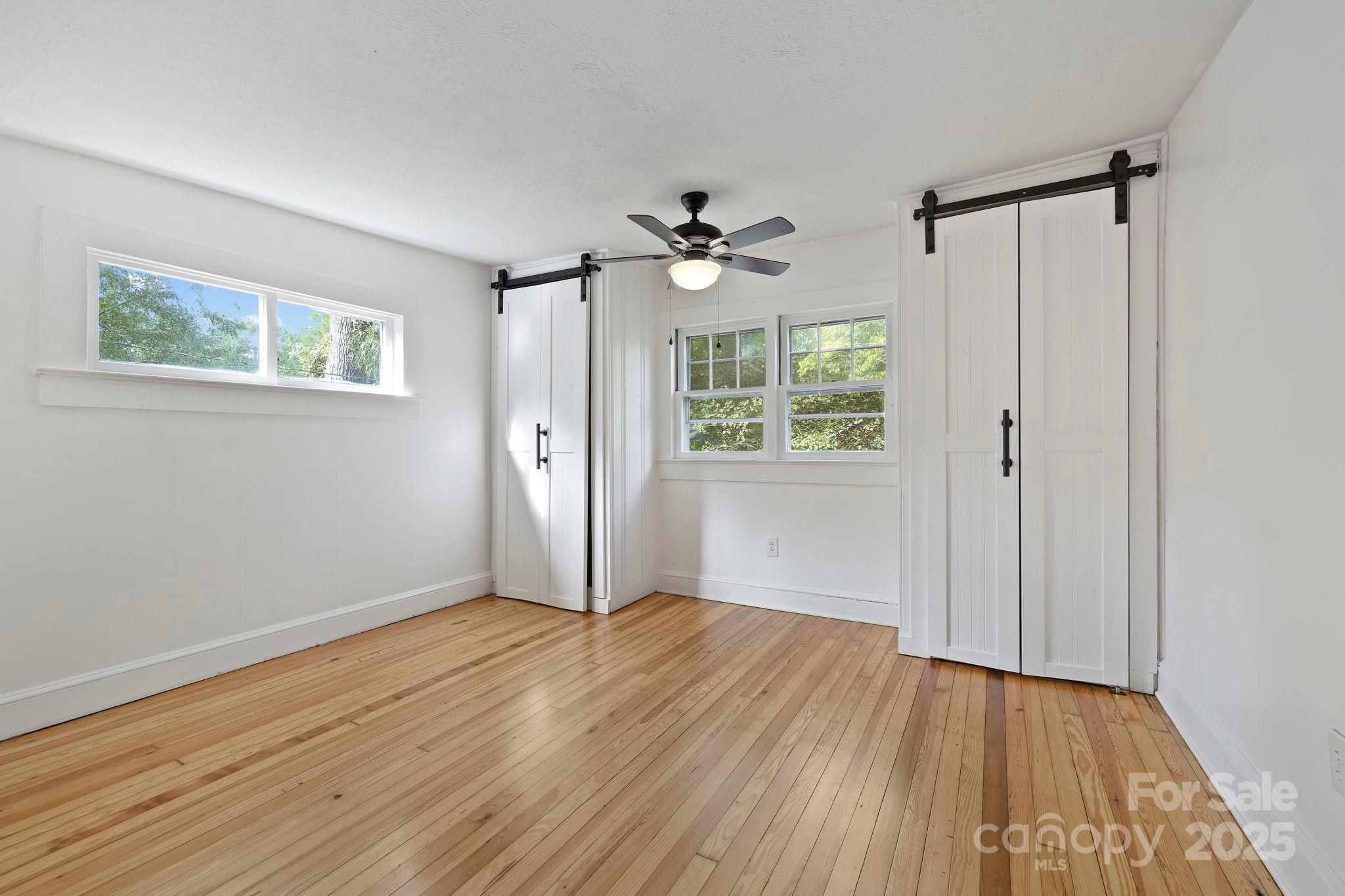 21 Maple Street Brevard, NC 28712 - Photo 22 of 29 an empty room with wooden floor chandelier fan and windows