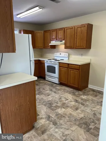 a kitchen with granite countertop a refrigerator stove top oven and sink