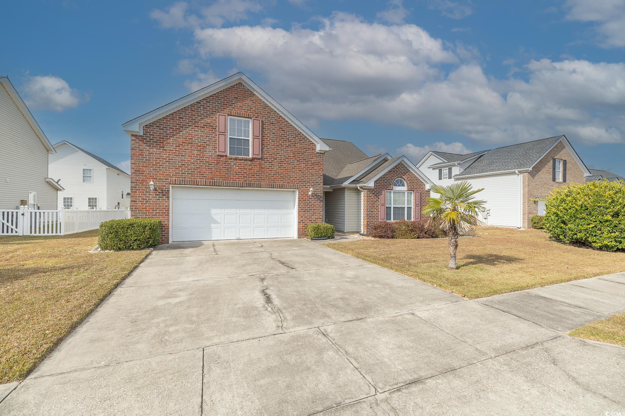 Traditional-style house featuring brick siding, driveway, and a garage